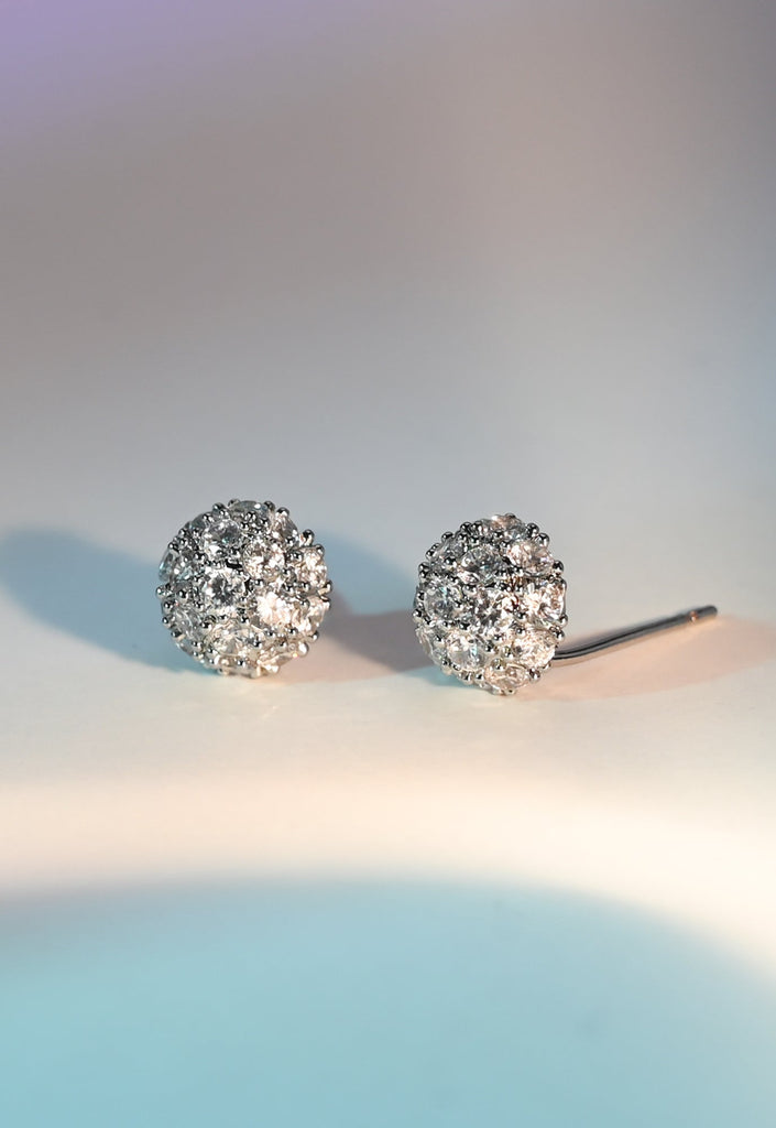Pair of silver earrings with clear stones on a light background