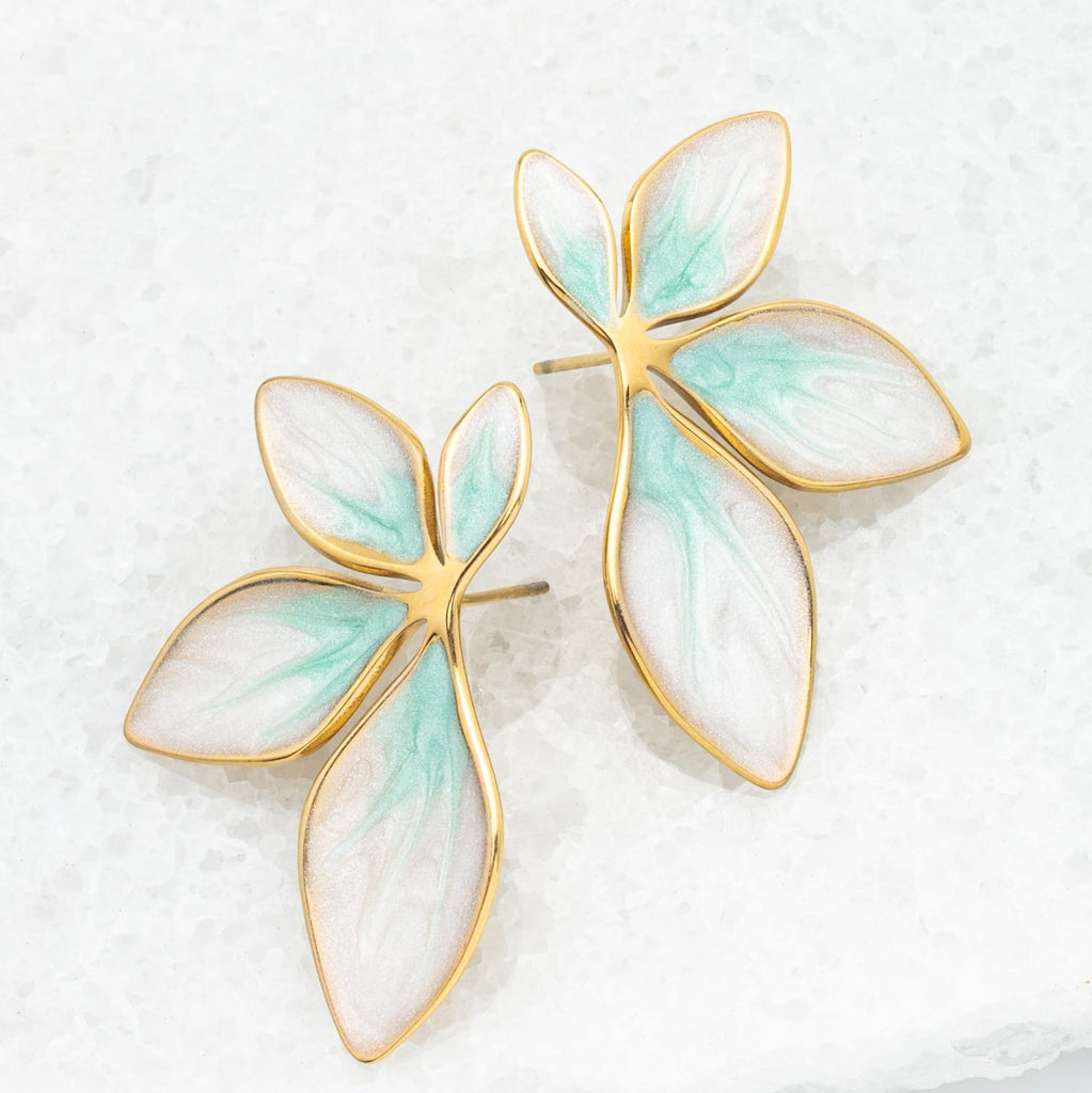 Gold and green leaf-shaped earrings on a light background