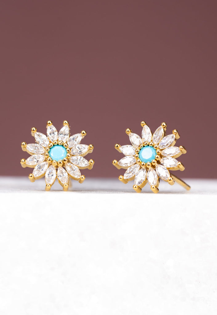 Pair of gold flower-shaped earrings with turquoise centers on a white surface.